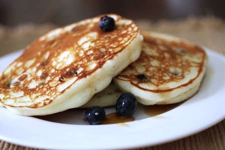 Gluten-Free Blueberry Ricotta Pancakes with syrup on a plate.