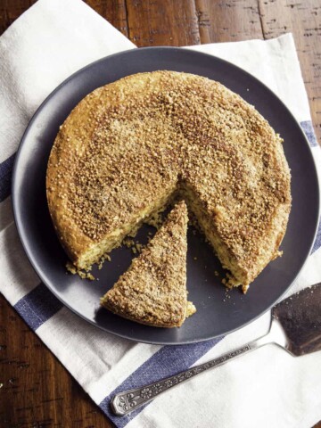 Almond flour coffee cake on plate. One slice is cut from the cake.