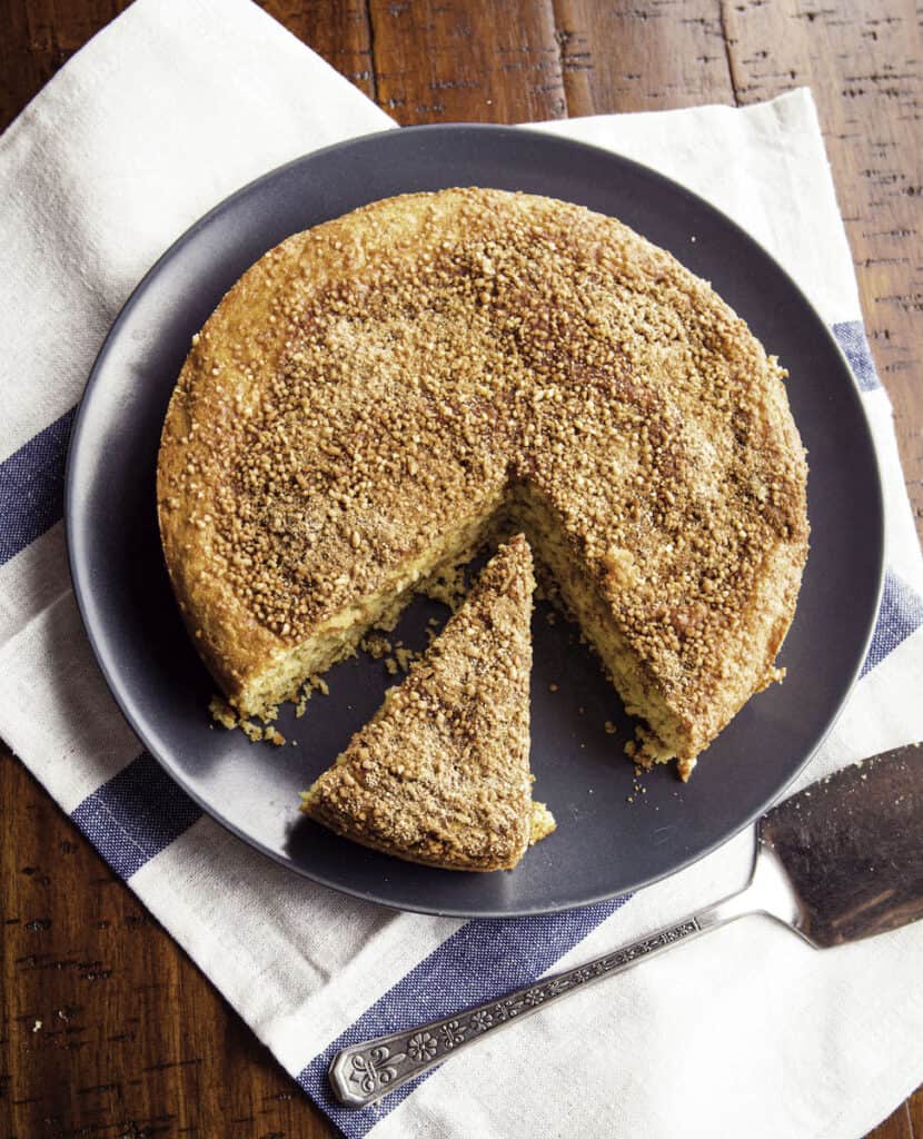 Almond flour coffee cake on plate. One slice is cut from the cake.