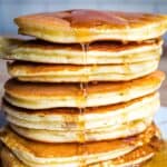 Stack of eight almond flour pancakes with maple syrup.