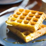 Two almond flour waffles on a plate with syrup.