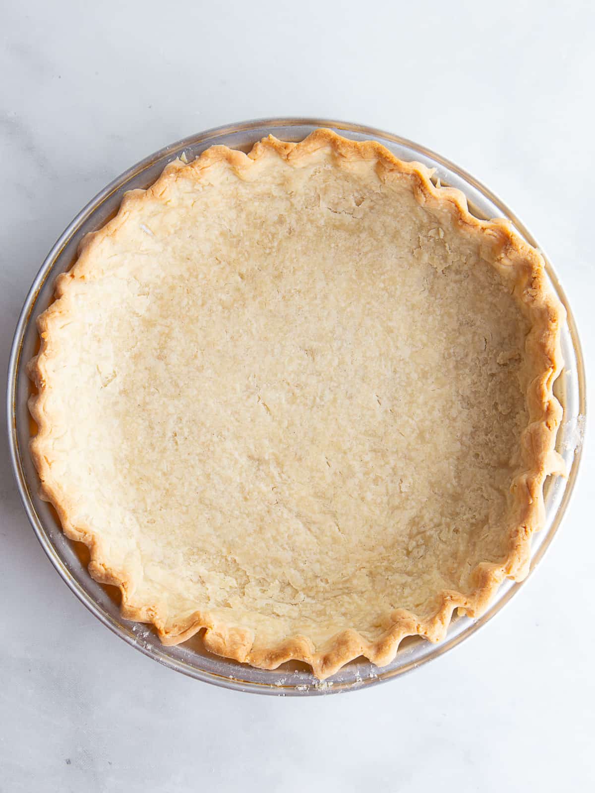 Empty baked gluten-free pie crust cooling in a pan.