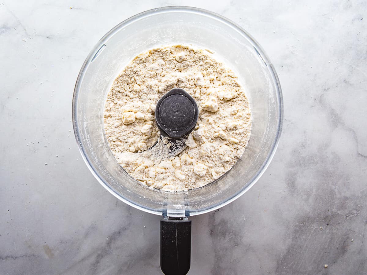 Butter cut into gluten-free flour for pie crust in the bowl of a food processor