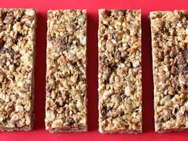 Chewy granola bars on red cutting board.