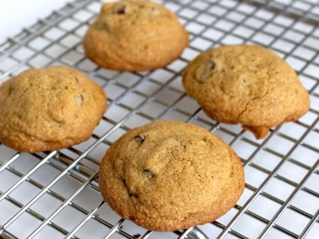 Four gluten-free chocolate chip cookies on a cooling rack.