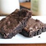 Two gluten-free brownies on a white platter.