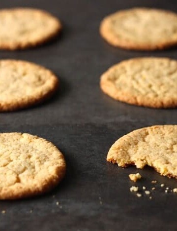 Momofuku Milk Bar's Corn Cookies on a baking sheet. One cookie has a bite taken out of it.