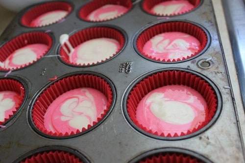 Pink and white cupcake batter in muffin cups.