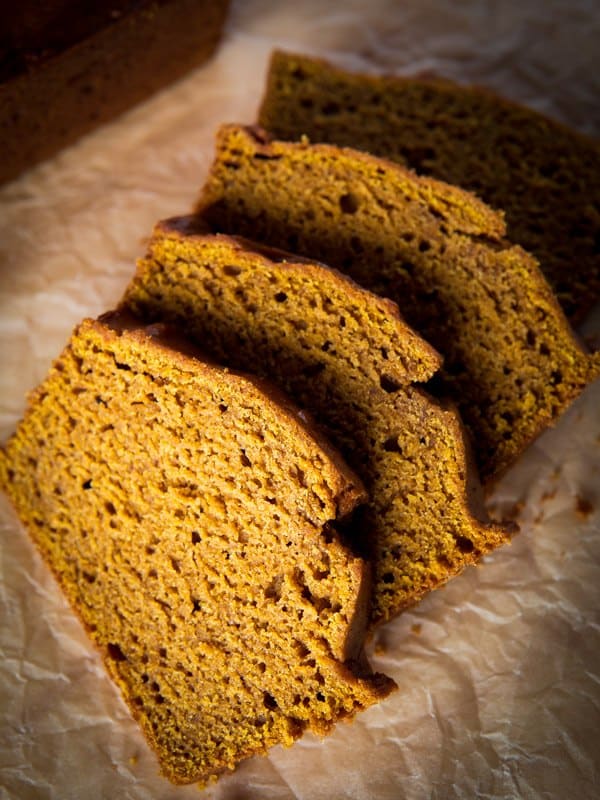 Sliced gluten-free pumpkin bread on brown parchment paper.