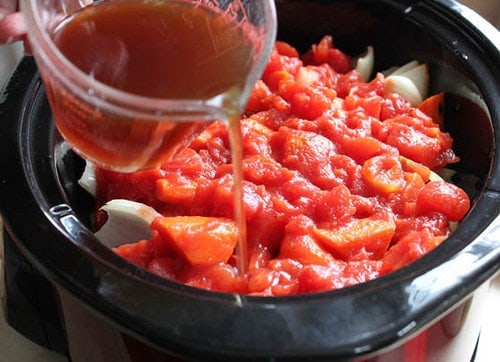 Pouring broth into slow cooker for paleo pot roast.