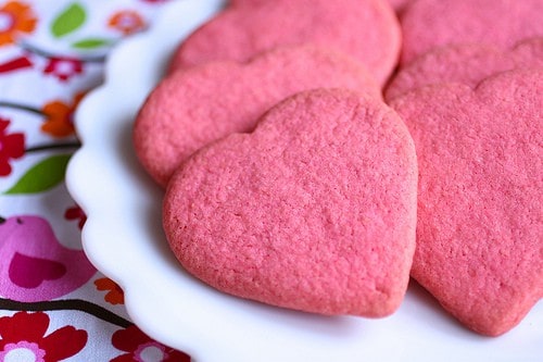 Pink gluten-free sugar cookie hearts on a plate.