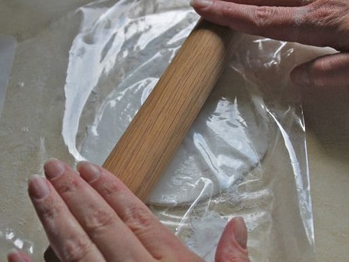 Rolling gluten-free flour tortilla dough with rolling pin.