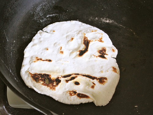 Cooked gluten-free Flour tortilla in a skillet with brown spots.