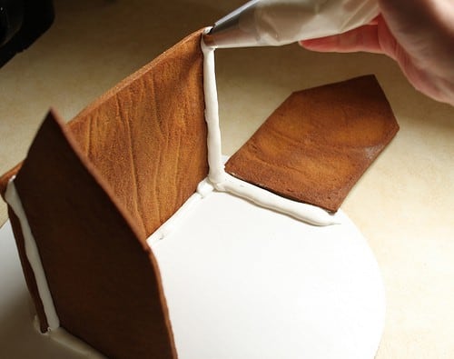 Frosting the edges of a gluten-free gingerbread house.