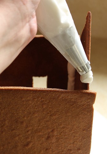 Placing icing on gluten-free gingerbread house.