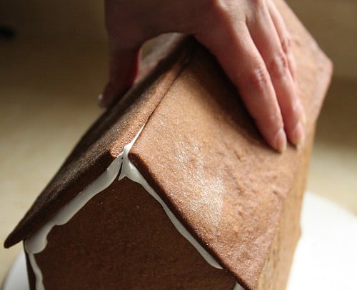 Placing roof on gluten-free gingerbread house.