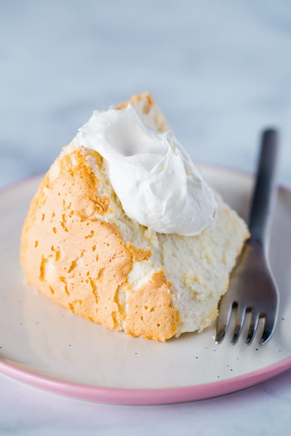 Slice of Gluten-Free Angel Food Cake on Plate with a Dollop of Whipped Cream