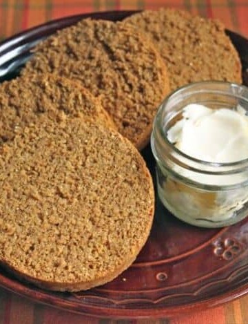 Gluten-Free Boston Brown Bread sliced on a plate with a dish of butter.