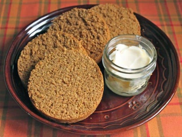 Gluten-Free Boston Brown Bread sliced on a plate with a dish of butter.