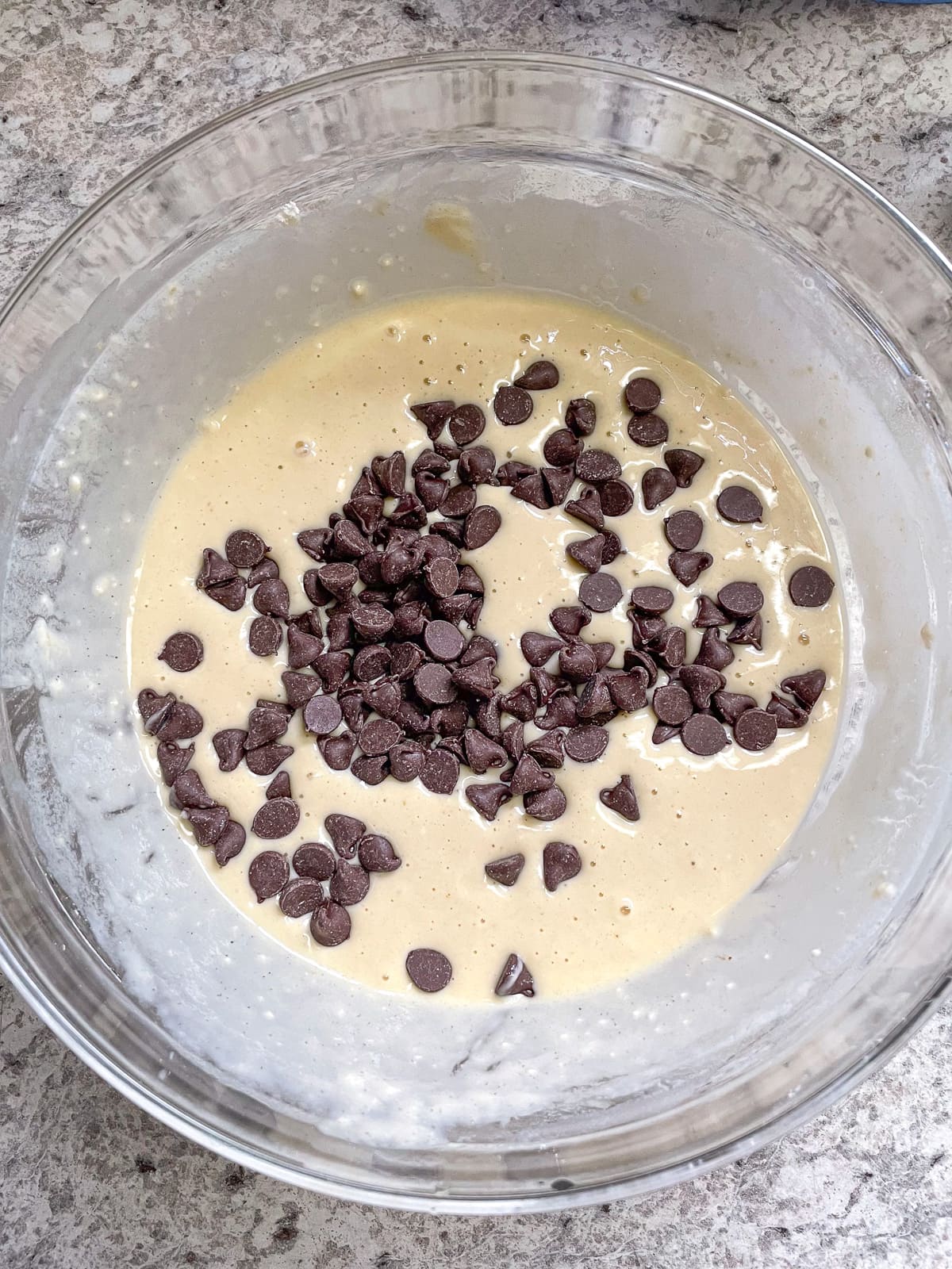 Chocolate chips sprinkled on gluten-free pancake batter.