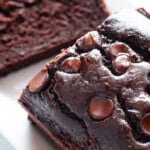 Gluten-free chocolate zucchini bread with chocolate chips on top. One slice has been cut from the bread.