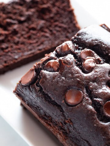 Gluten-free chocolate zucchini bread with chocolate chips on top. One slice has been cut from the bread.