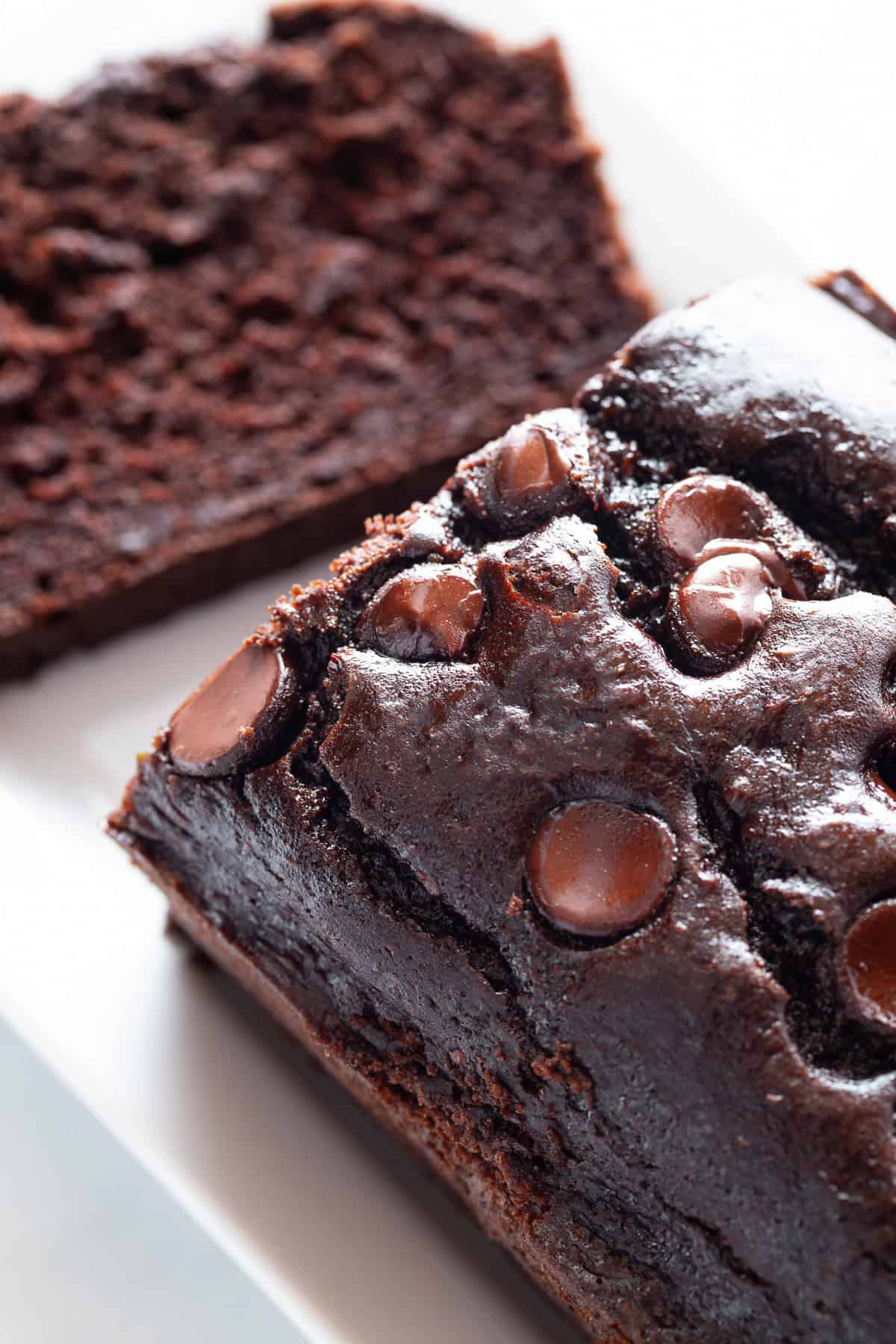 Gluten-free chocolate zucchini bread with chocolate chips on top. One slice has been cut from the bread.