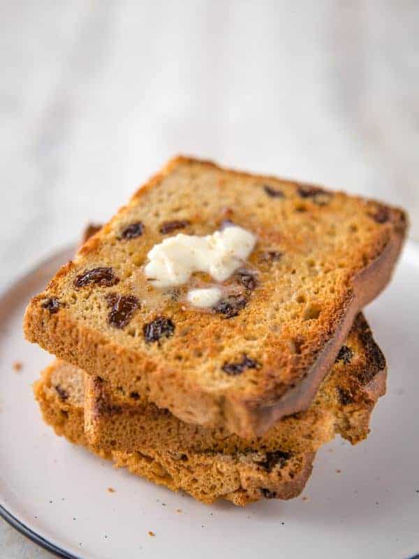 Stack of Toasted Gluten-Free Cinnamon Raisin Bread. Top slice is buttered. 