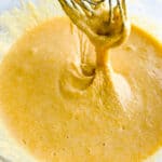 Gluten-free cornbread batter in bowl and falling off a whisk.