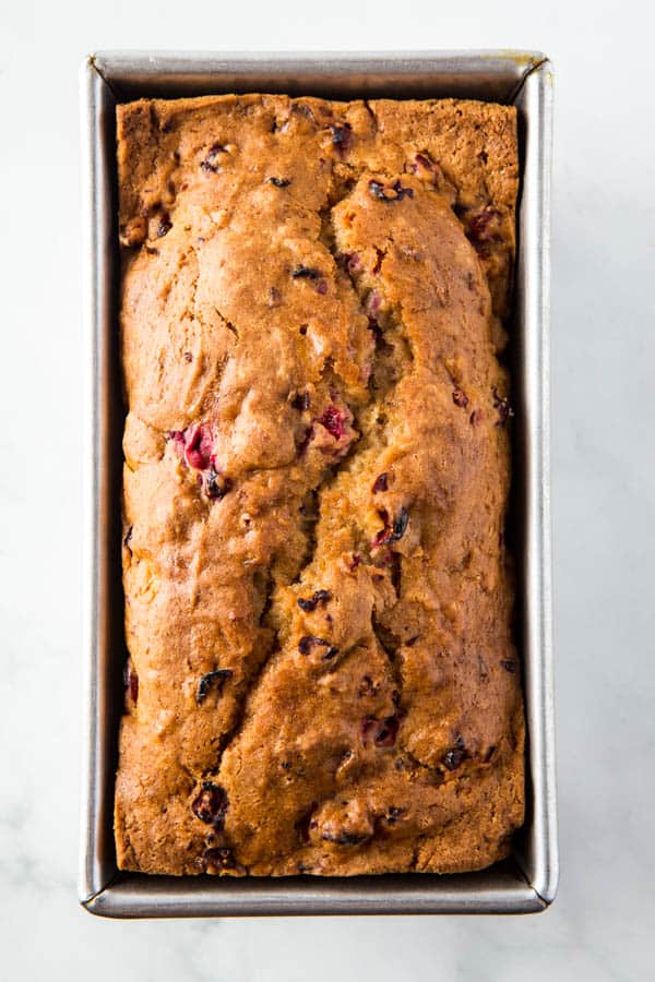 Baked loaf of gluten-free cranberry bread in pan. 