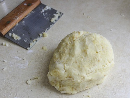 Gluten-free gnocchi dough on counter with a bench scrapper sitting behind it.