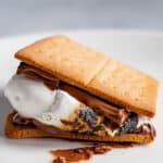 Gluten-free graham cracker used as the base for a s'more. A toasted marshmallow and chocolate are sandwiched between the graham crackers.