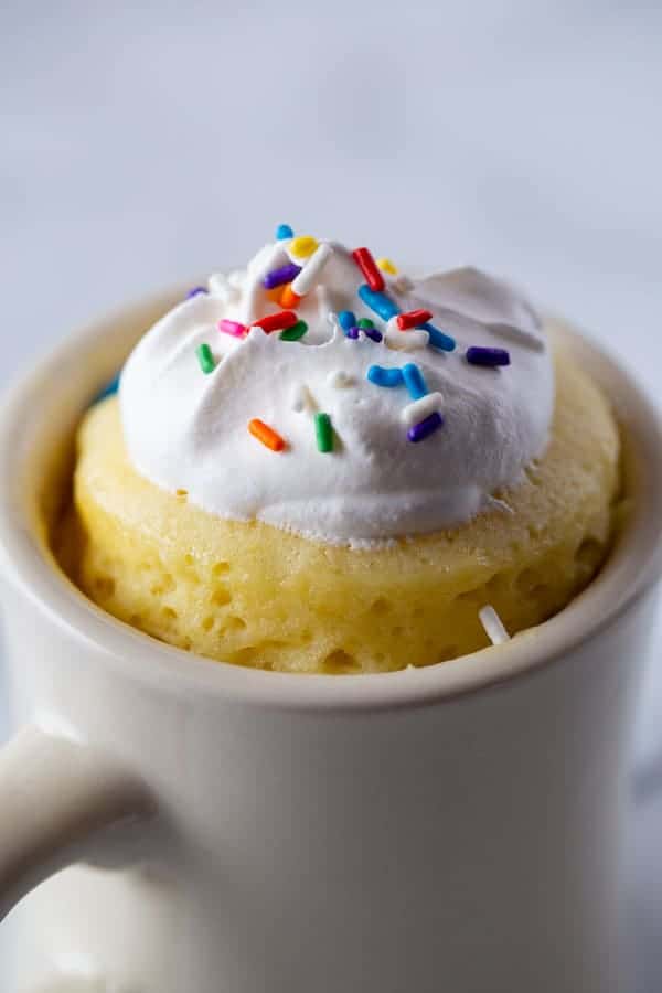 Gluten-Free Mug Cake in White Mug. Topped with Whipped Cream and Sprinkles