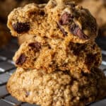 A stack of three gluten-free oatmeal cookies. The top two cookies are broken in half to show the chocolate chips insides.