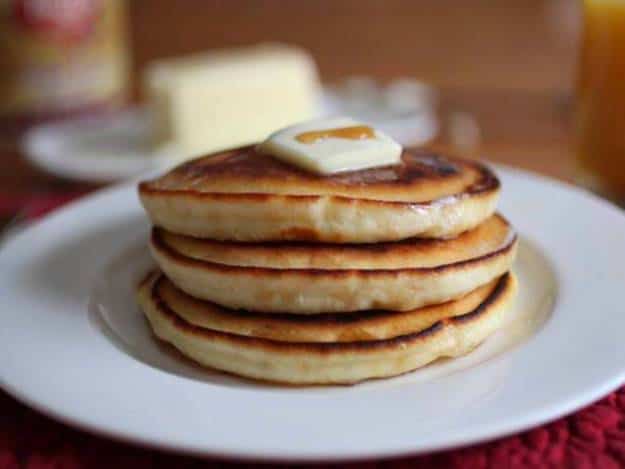 Stack of gluten-free pancakes with pat of butter and drizzle of syrup.