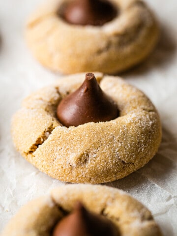 A gluten-free peanut butter blossom sits on a piece of parchment paper.