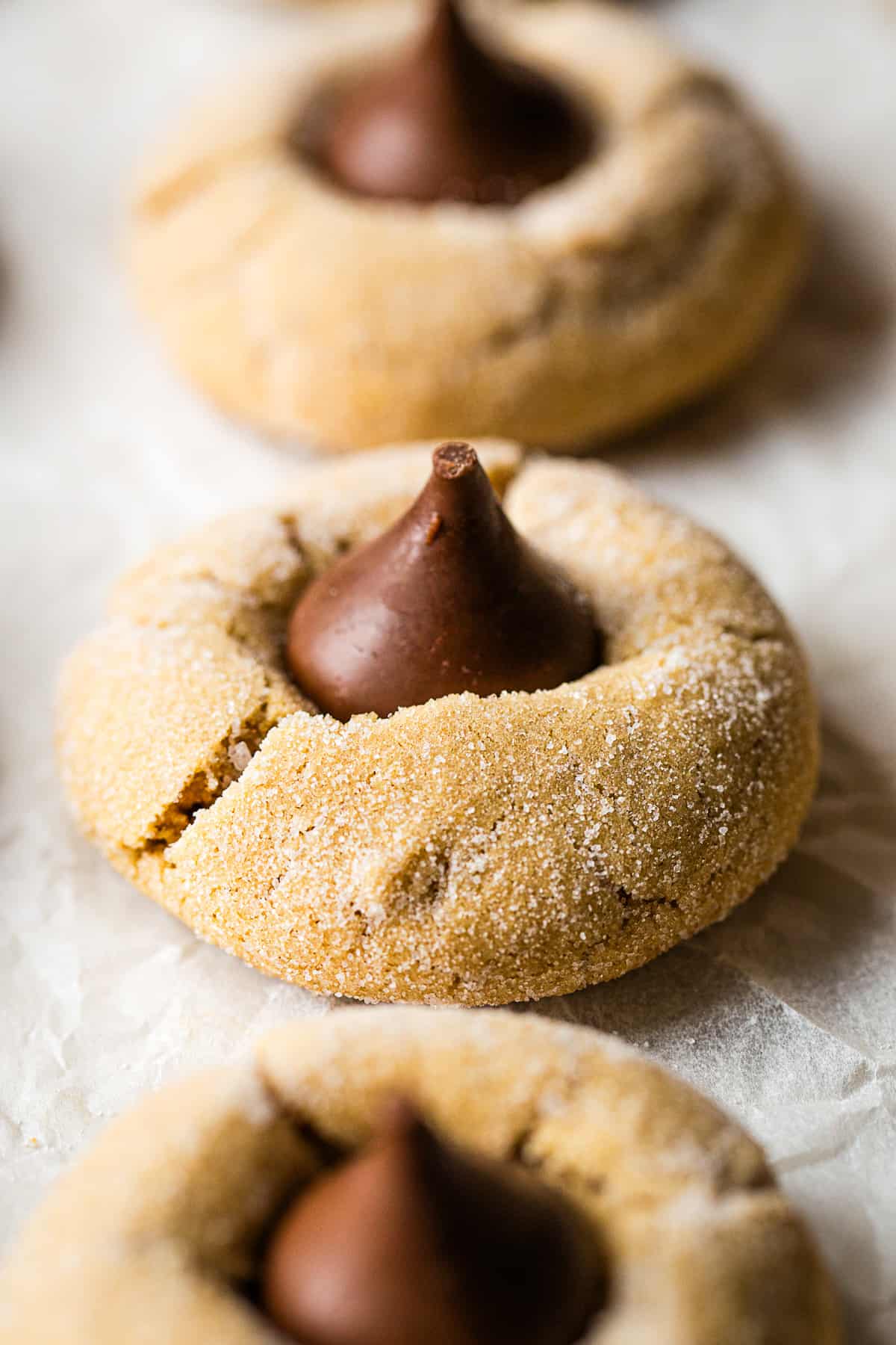 A gluten-free peanut butter blossom sits on a piece of parchment paper.