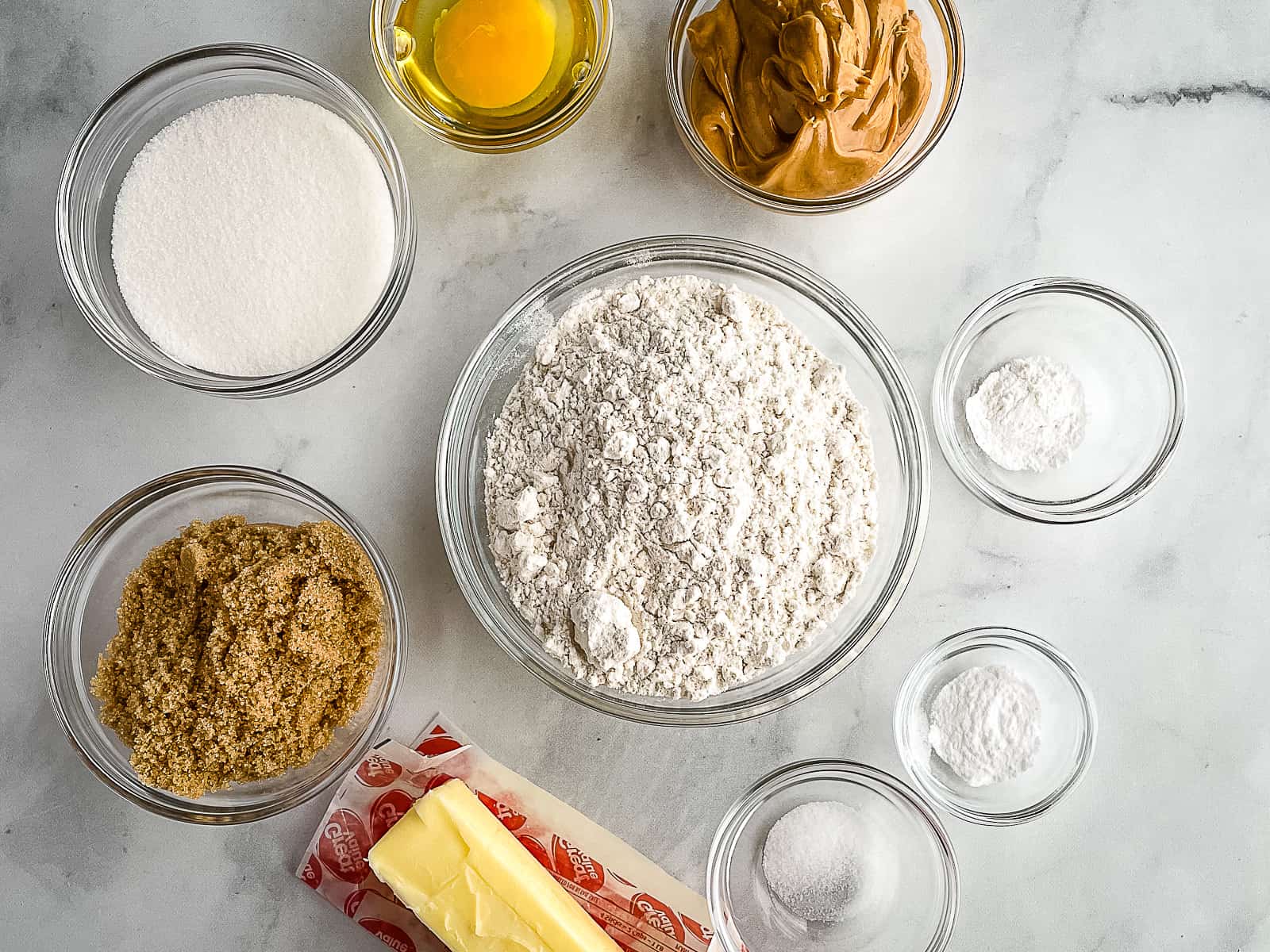 Gluten-free peanut butter cookie ingredients in bowls on a counter.