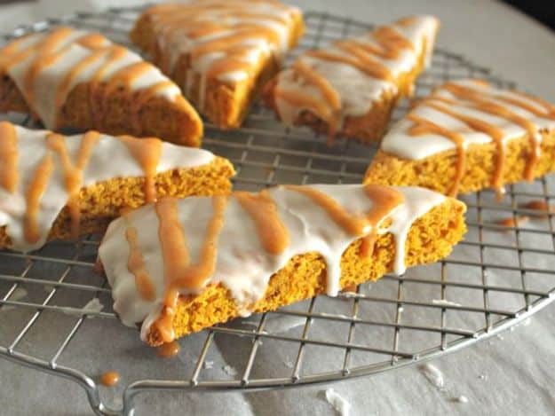 Gluten-Free Pumpkin Scones on a wire rack. Scones are iced with vanilla icing and drizzled with a spice glaze.