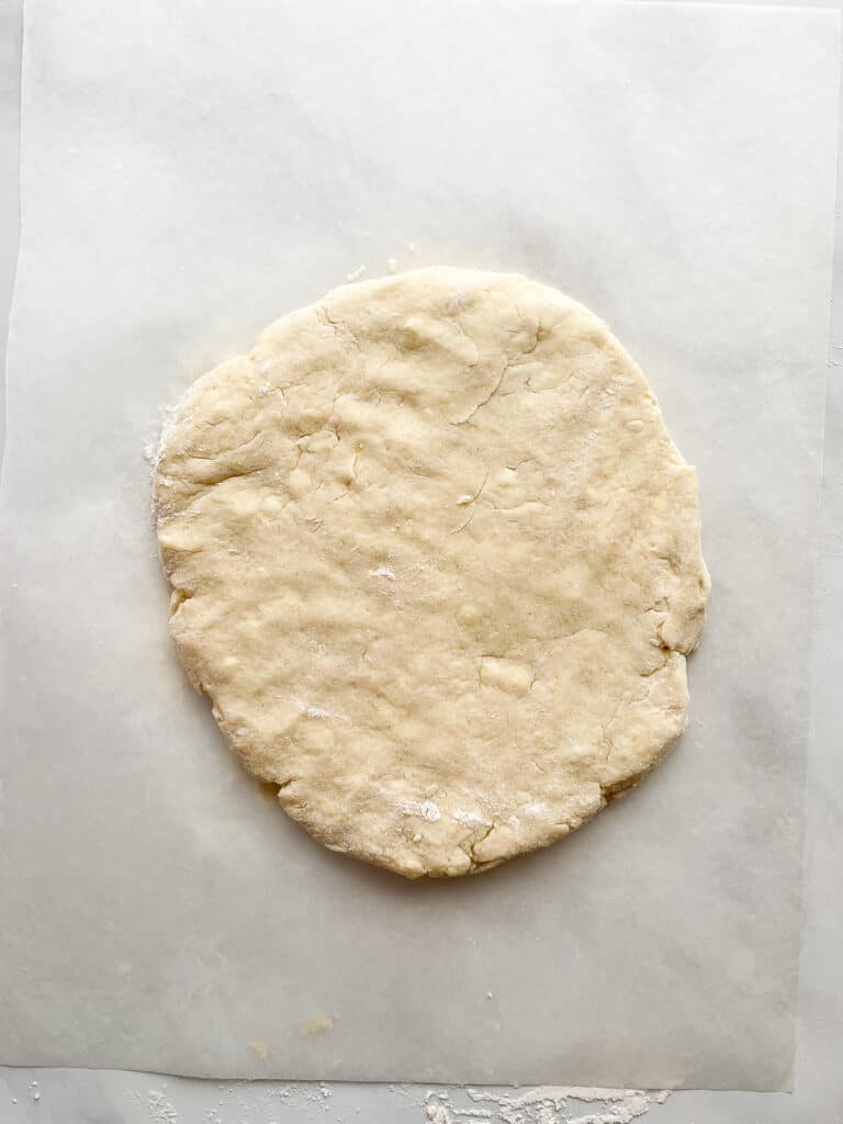 Gluten-free scone dough pressed out on a piece of parchment.