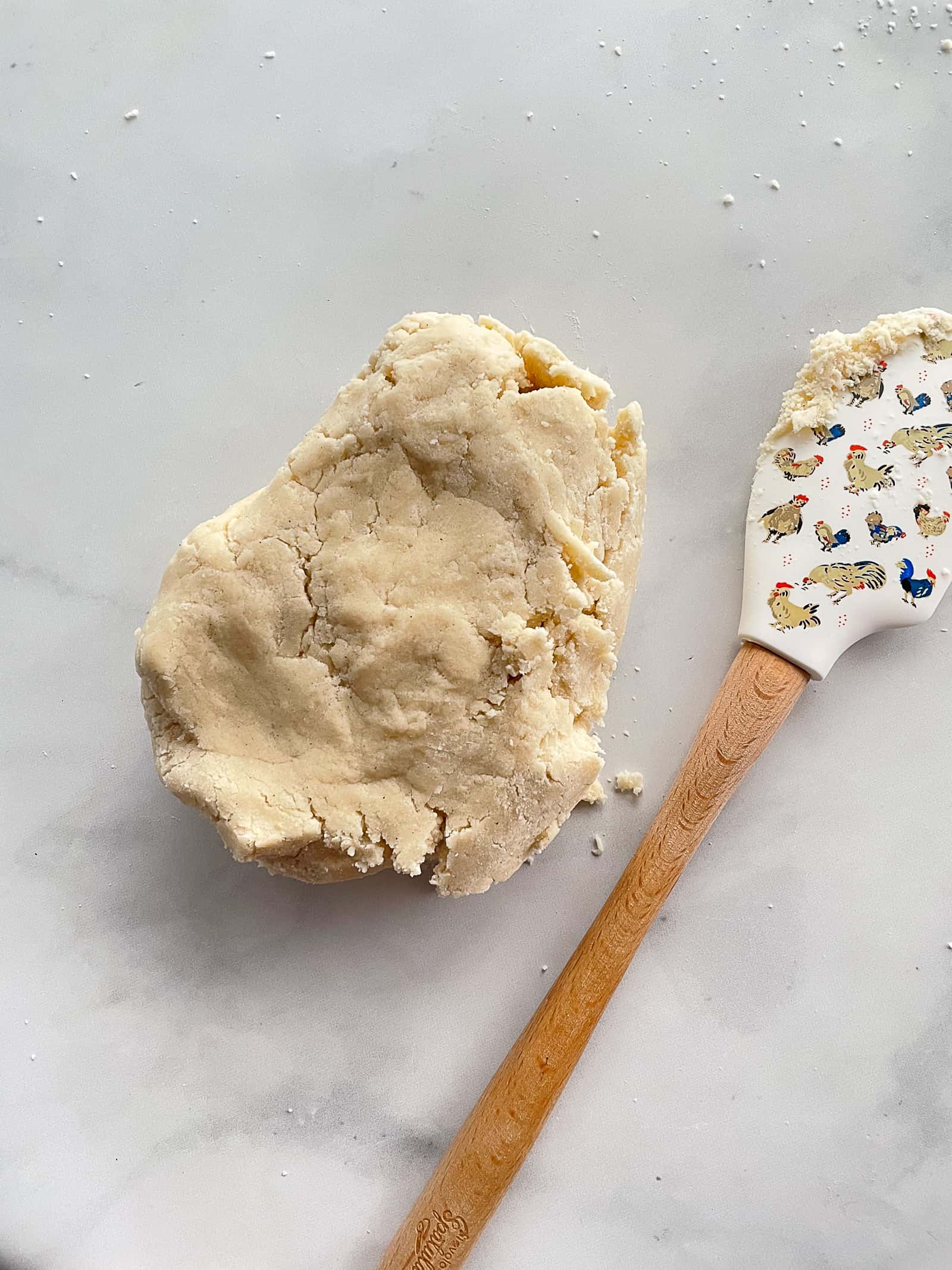 Gluten-free shortbread dough on a counter. Rubber spatula is on the right side.