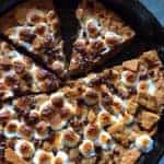 Gluten-Free S'more Cookie in Skillet. Cut and topped with browned marshmallows and chocolate chips.