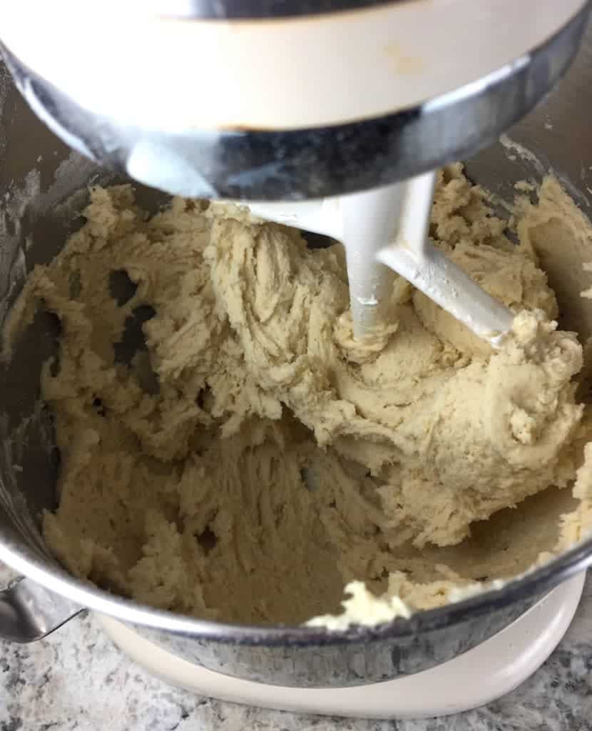 Gluten-free soft sugar cookie dough in bowl of a stand mixer.