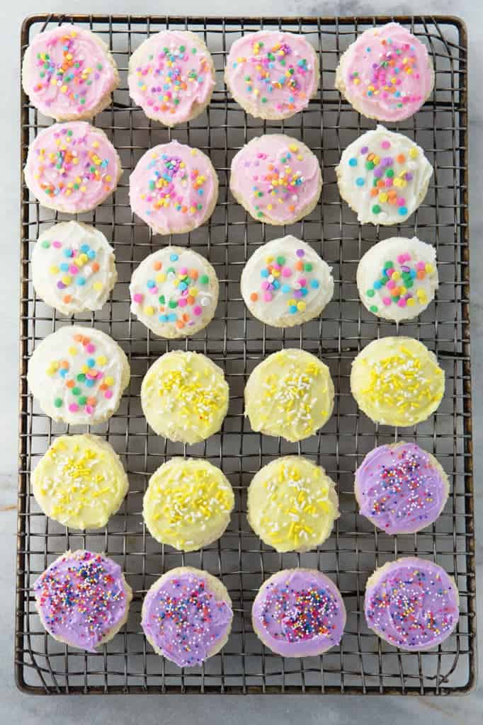 Gluten-Free Soft Sugar Cookies on a wire rack. Cookies are frosted with buttercream and and topped with sprinkles.