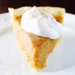 Gluten-Free Sweet Potato Pie topped with whipped cream on a white plate.