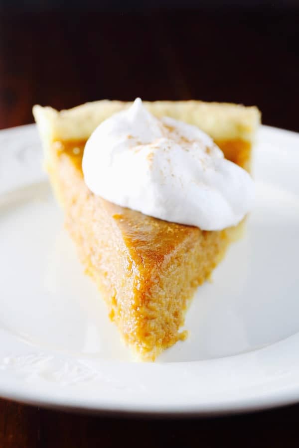 Gluten-Free Sweet Potato Pie topped with whipped cream on a white plate.