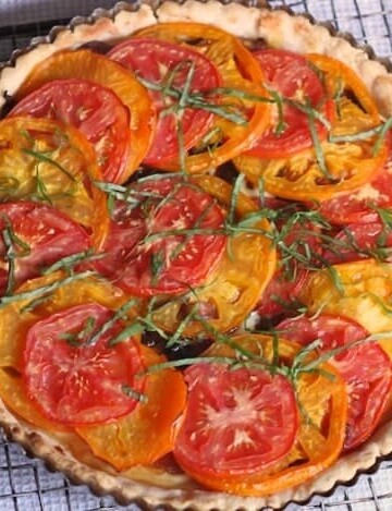 Gluten-Free Tomato Tart on a wire rack. The tart is topped with shredded basil.