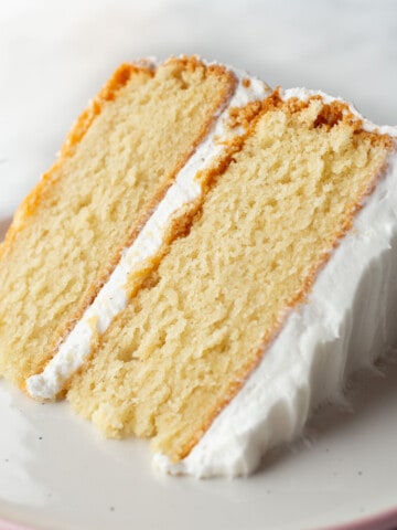 Gluten-free vanilla cake on a plate. The cake is frosted with vanilla buttercream.