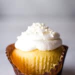 Gluten-Free vanilla cupcake. White frosting. Unwrapped in front.