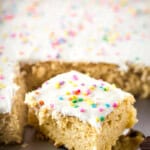 Gluten free vanilla sheet cake in the pan with frosting and sprinkles on top.